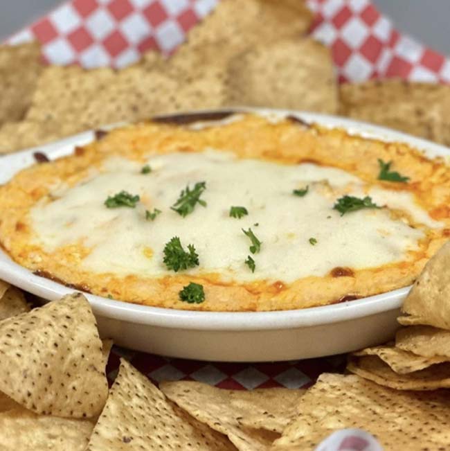 A cheesy dip topped with herbs, perfect for pairing with a drink at a Holmen Wisconsin bar.