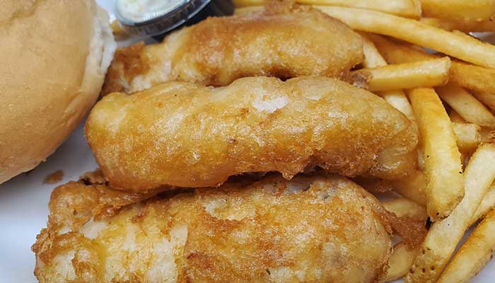 Three pieces of fried fish with fries, a bun, and tartar sauce at Features Sports Bar & Grill.