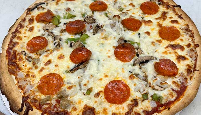 A Holmen Wisconsin food favorite: pizza with pepperoni, veggies, cheese—best with a drink.