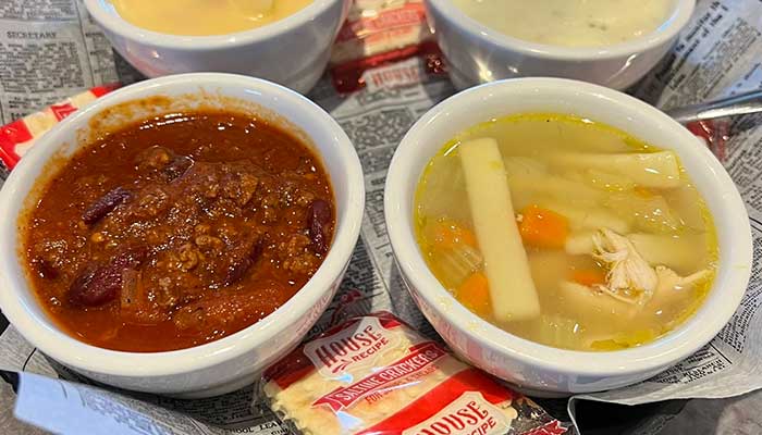 Three bowls of soup and chili with crackers at Features Sports Bar & Grill, served on a tray.