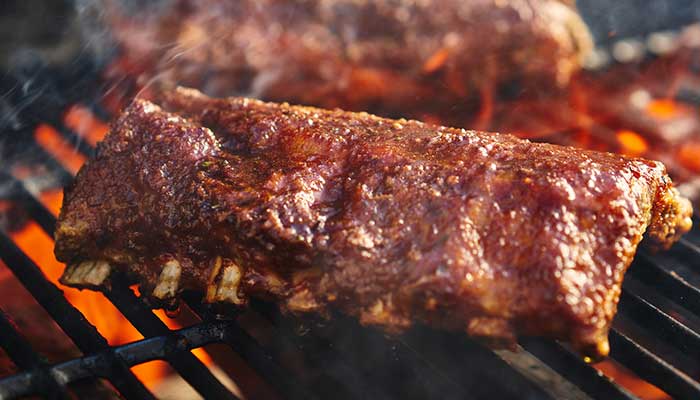Barbecue ribs cooking on a grill at a Holmen Wisconsin bar, smoky and glazed, perfect with a drink.