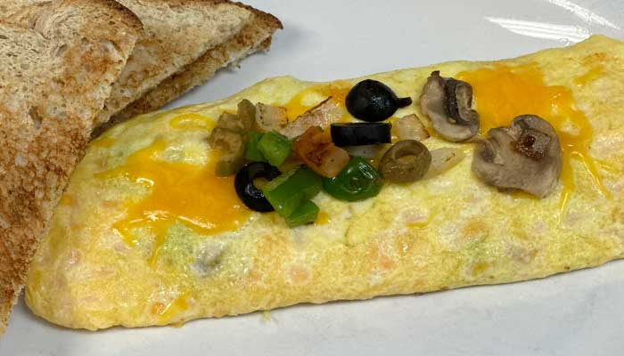 Omelet with cheese, mushrooms, olives, peppers, and toast—perfect food for any bar brunch.