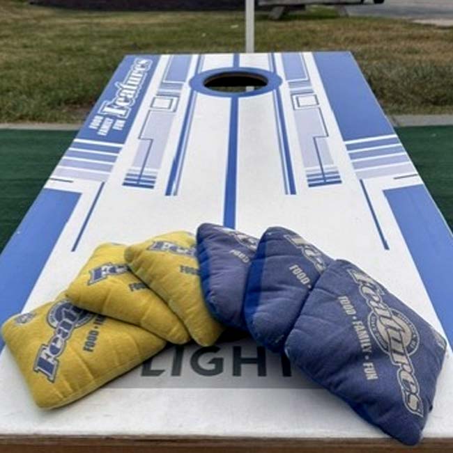 Cornhole board at Holmen Wisconsin Restaurant, featuring blue and yellow bean bags for play.