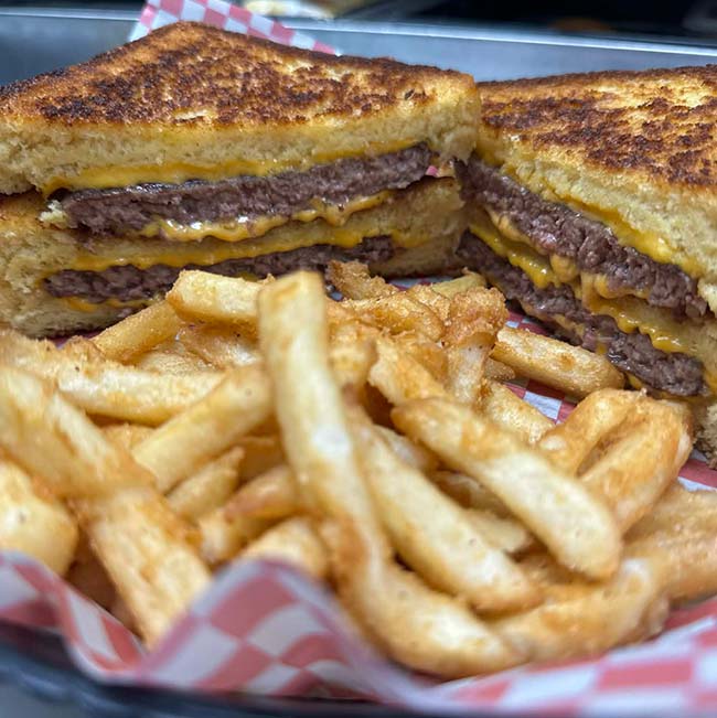 Bar food classic: grilled cheese burgers with melted cheese, served with crispy fries.