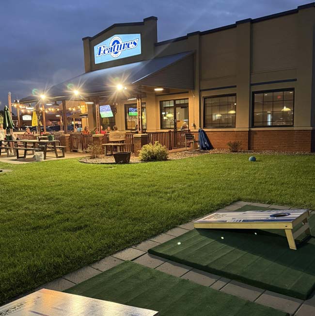 Outdoor seating at Features Sports Bar & Grill in Holmen, Wisconsin with food and cornhole.